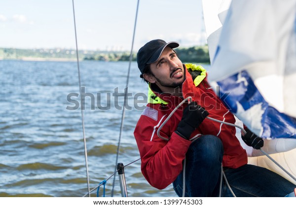 Yacht\
sailor pulling rope. Man working on\
sailboat.