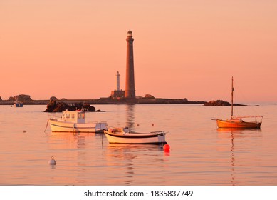 Yachts and boats anchored on mooring in Lilia bay near the Île Vierge lighthouse at sunset. Plouguerneau, Finistère, Brittany, France. Clear pink sky. Travel destinations, landmarks, recreation - Powered by Shutterstock