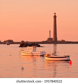 Yachts and boats anchored on mooring in Lilia bay near the Île Vierge lighthouse at sunset. Plouguerneau, Finistère, Brittany, France. Clear pink sky. Travel destinations, landmarks, recreation