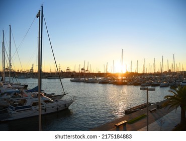 Yachts and boats in silhouette of sunset in Marina. Sunset at port. Skiff and Sailboat in harbour. Luxury yacht and fishing motor boat in yacht club at Mediterranean Sea. Yacht in sunrise in Harbor.