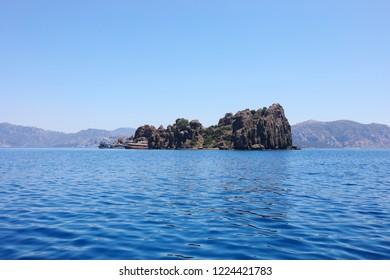 Yachts are near rocky sea coast at sunny summer day, blue water and sky