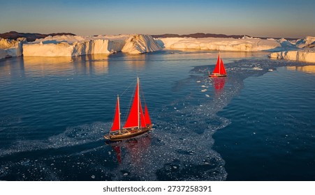 Yachts with red sails in the light of the setting sun. Greenland. Denmark.