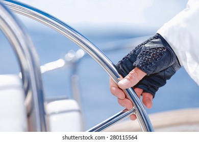 Yachtsman holding the wheel / Hand of a yachtsman holding the wheel on a sailing boat