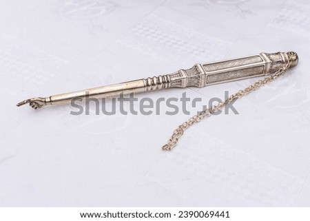 A yad or pointer with a small hand and finger used to assist the Torah reader to follow the Hebrew text during a Jewish prayer service.