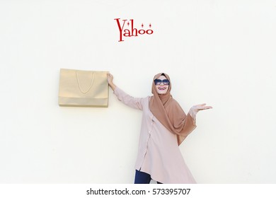 Yahoo : The Magic Marketing and Positive Thinking Words seller should use, over the Malaysian lady holding a Gold Paper Bag with authentatic smile and isolated white background.