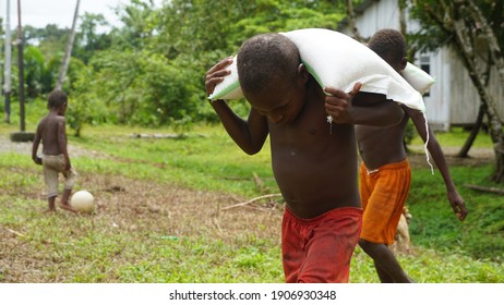 Yahukimo, Papua, Indonesia – Januari 6, 2021 : A child carrying a sack of rice.