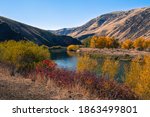 Yakima Canyon and river in fall season. Blue sky reflects in water. Red, yellow and orange colors of foliage on both riverbanks