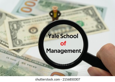 Yale School of Management.Magnifying glass showing the words.Background of banknotes and coins.basic concepts of finance.Business theme.Financial terms. - Shutterstock ID 2156850307