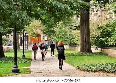 YALE UNIVERSITY, NEW HAVEN, CONNECTICUT, USA - OCTOBER 2017: Students Walking On A Path Through Old Campus At Yale. Green Trees Surround The Old Brick Buildings And A Doorway Can Be Seen Beyond