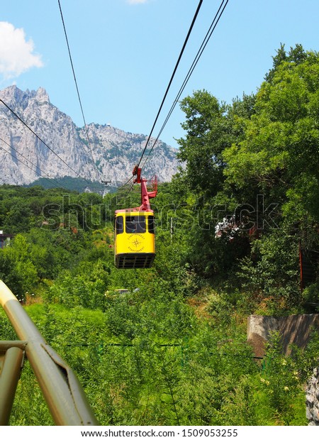 Yalta, Russia-July 16,\
2019. Cableway climbs the mountain AI-Petri, one of the most\
beautiful mountain peaks of the Crimea, is part of the Yalta\
mountain forest reserve.