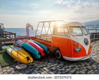 Yalta, Ukraine - October 31,2021: Old Retro Vintage Bright Orange White VW T1 Bulli Camper Van Bus Customized As Kayak Boat Trailer Parked Near Sea Coast Beach Road Against Sunset Sunny Sky On Day