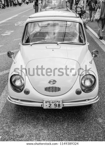 YAMAGUCHI, JAPAN - APRIL 8, 2018: A front view,\
black and white photo of a cute, classic Subaru 360 compact car\
parked on a city\
street.