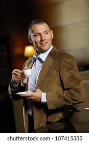 Yang man dressed in brown jacket with cup of coffee