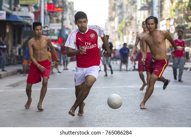 YANGON, MYANMAR - JANUARY 4, 2016: Kids And Teenagers Having Fun Playing Football On The Streets Of Yangon , Myanmar On January 4, 2016.