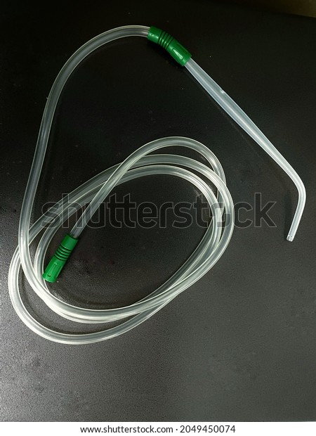 A Yankauer suction set with suction tubing
placed on a dark background 
