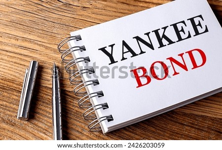 YANKEE BOND text on a notebook with pen on wooden background