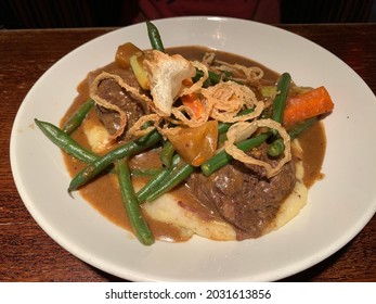 Yankee Pot Roast Serving Over Mashed Potatoes And Topped With Crispy Onions.