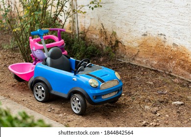A yard with two children's toys in it. Big old toy car in summer garden, outdoors. Garden toys