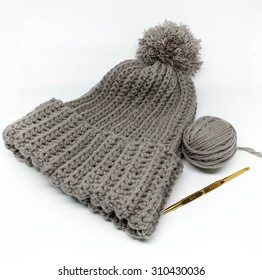 Yarn Ball And Gray Crochet Hat With A Golden Needle