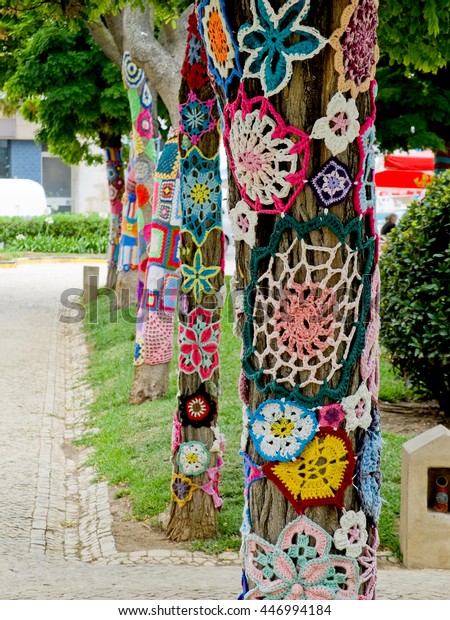 Yarn bombing.  A tree dressed with knitted colorful\
wool. European park.