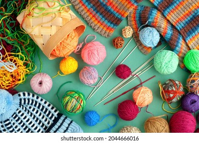 Yarn for knitting clothes for cold seasons. Lots of bright yarn are scattered on the table. Knitting is a kind of needlework. Balls of yarn and knitting needles on a turquoise background.