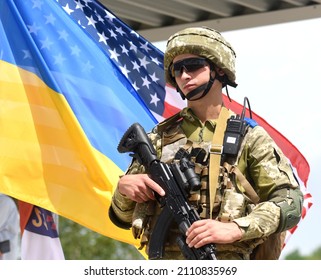 Yavoriv, Ukraine - July 27, 2021. Ukrainian soldier near  flags of Ukraine and US during the Three Swords 2021 multinational military exercise near Yavoriv in western Ukraine.