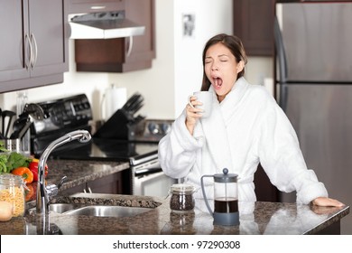 Yawning coffee woman in morning standing by kitchen table at home. Sleepy tired multiracial female model in bathrobe drinking coffee from french press. - Powered by Shutterstock