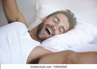 Yawning and stretching man waking in bed