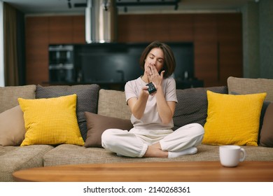 Yawning Young Girl Holding Tv Remote Controller Watching Boring Program, Cover Mouth, Feel Sleepy, Sitting On Sofa