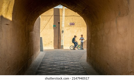 Yazd, Iran - May 2019: Kids riding a bicycle in a narrow street of old city Yazd