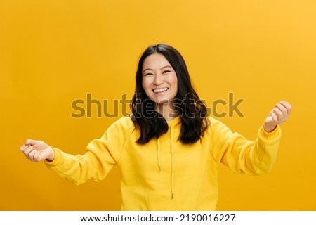 Yeah, I did it. Overjoyed Asian student young woman in yellow hoodie sweatshirt raise fists up smiling posing isolated on over orange studio background. Cool offer. People Emotions concept