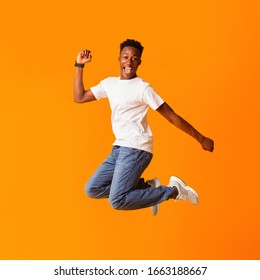 Yeah. Excited Screaming African Man Jumping While Celebrating His Victory Or Triumph Over Orange Background