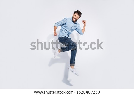 Yeah! Full size profile photo of funny indian guy jumping high rejoicing raising fists crazy competitive mood wear casual denim clothes isolated white color background