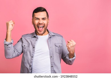 Yeah! Happy Winner! Happy Young Handsome Man Celebrating Victory Gesturing And Keeping Mouth Open While Standing Isolated Over Pink Background.