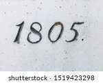 The year 1805 carved in stone and painted in black – taken from an inscription produced that year. Sparsely covered with lichen