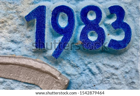 The year 1983 carved in a stone to indicate the year the building was erected. Produced at that time