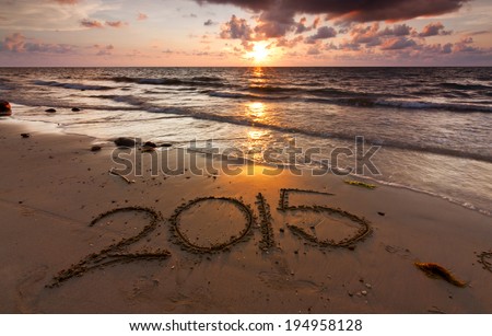 Year 2015 written on sand at sunset