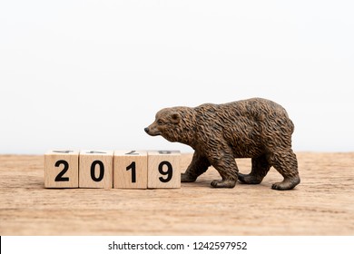 Year 2019 financial, equity or stock investment bear market concept with bear figure waking with stack of cube block building year number 2019 on wooden table white background with copy space. - Powered by Shutterstock