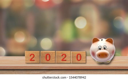 Year 2020 Financial Goal. Piggy Bank With Wooden Cube Block With Number 2020 On Table And Bokeh Background.