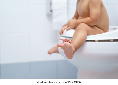 A year and 3 months old Asian baby sit on a kid bathroom accessory toilet