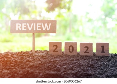 Year end 2021 review and summary concept. Wooden blocks in dark sunset background