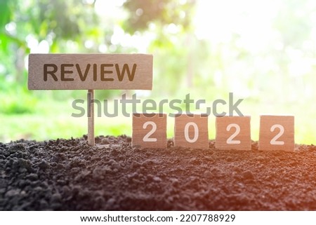 Year end 2022 review and summary concept. Wooden blocks in dark sunset on natural background.	