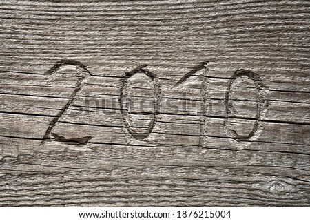 Year number 2010 carved into textured wood background