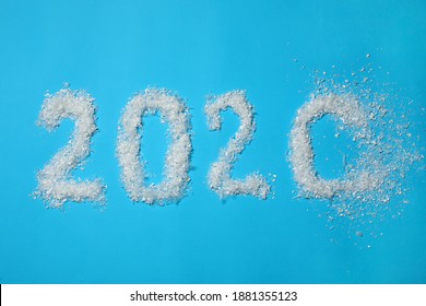 Year Number 2020 Made Of Artificial Snow Getting Blown Away On Light Blue Background, Flat Lay