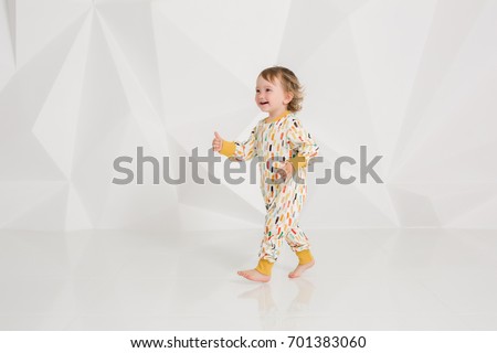 Year-old child standing near white wall in studio