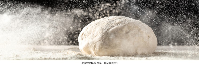 yeast dough for bread or pizza on a floured surface, with flour splash. Cooking bread. Kneading the Dough. Long banner format