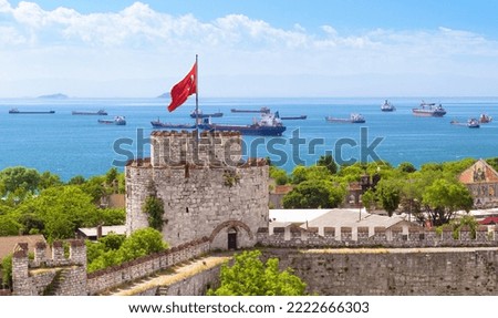 Yedikule Fortress overlooking sea with vessels, Istanbul, Turkey. Scenic view of old castle, Turkish flag and cargo ships. Theme of grain export deal, Ukraine war, oil, shipping and travel.