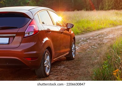 Yekaterinburg, Russia - August 2022: Car In The Field At Sunset. Close-up Of An Orange Car On A Country Road, Car Travel At Sunset Background, Travel From Nature By Car, Journey, Summer And Lifestyle.