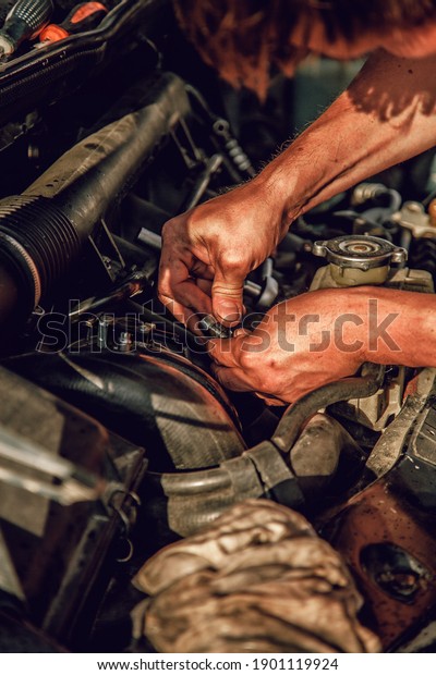 \
Yekaterinburg, Russia - June, 2020:\
[male strong dirty hands in oil repair a car under the\
hood]