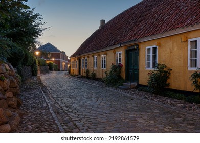 Yelllow Detatched House With Roses Along The Wall Iluminated By Streetlamps In The Soft Evening Light, Mariager, Denmark, August 6, 2022